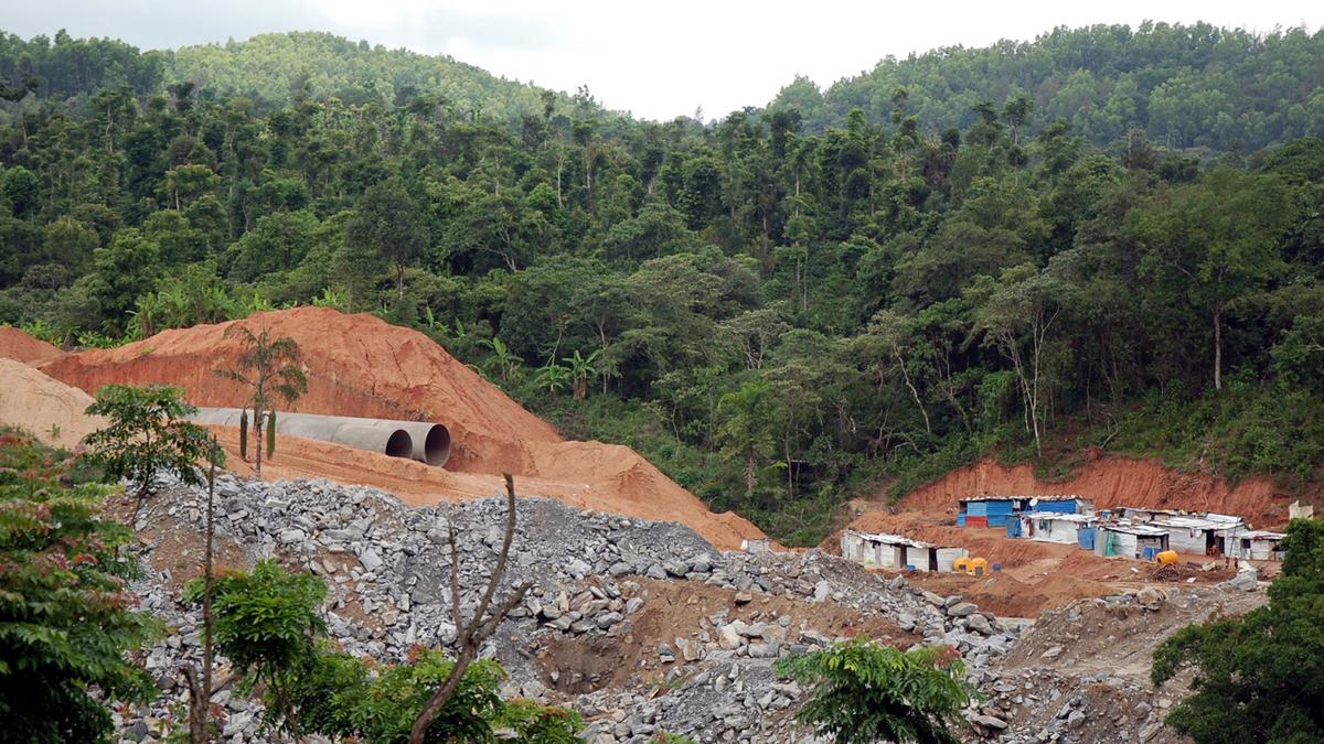 Heavy construction machinery slicing through sensitive forested hillsides